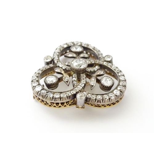 583 - A yellow gold brooch / pendant of trefoil form set with a profusion of diamonds with floral detail. ... 