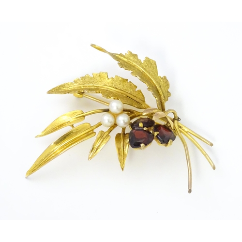 584 - A 9ct gold brooch of foliate form set with garnets and pearls. Approx. 2