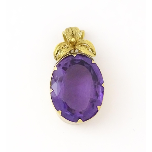 587 - A yellow metal pendant set with central amethyst, and filigree style floral detail. Approx. 1