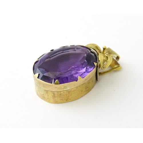 587 - A yellow metal pendant set with central amethyst, and filigree style floral detail. Approx. 1