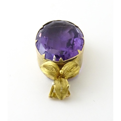 587 - A yellow metal pendant set with central amethyst, and filigree style floral detail. Approx. 1