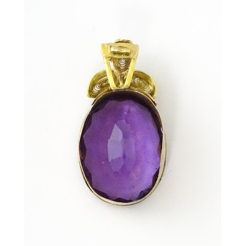 587 - A yellow metal pendant set with central amethyst, and filigree style floral detail. Approx. 1