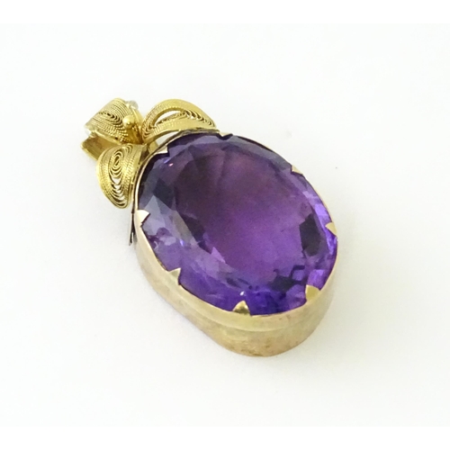 587 - A yellow metal pendant set with central amethyst, and filigree style floral detail. Approx. 1