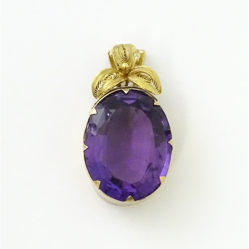 587 - A yellow metal pendant set with central amethyst, and filigree style floral detail. Approx. 1