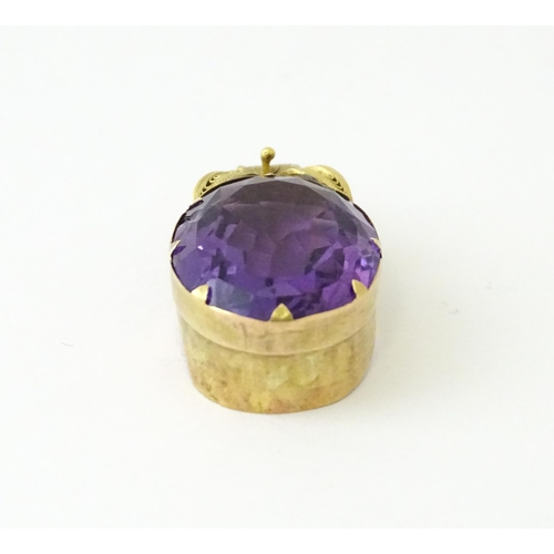 587 - A yellow metal pendant set with central amethyst, and filigree style floral detail. Approx. 1