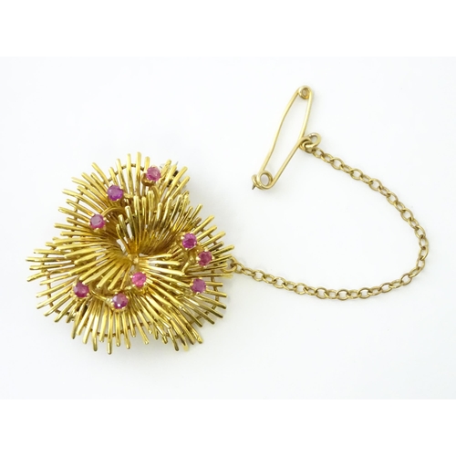 591 - An 18ct gold brooch / pendant of stylised floral form set with 9 rubies. Approx. 1 1/4