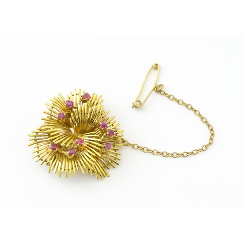 591 - An 18ct gold brooch / pendant of stylised floral form set with 9 rubies. Approx. 1 1/4