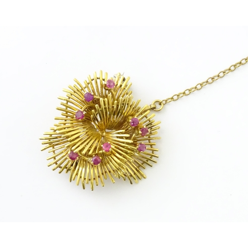 591 - An 18ct gold brooch / pendant of stylised floral form set with 9 rubies. Approx. 1 1/4