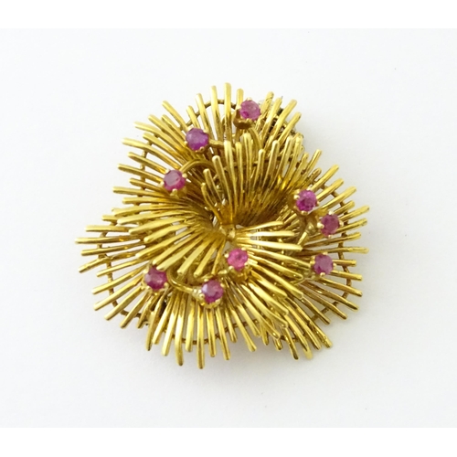 591 - An 18ct gold brooch / pendant of stylised floral form set with 9 rubies. Approx. 1 1/4