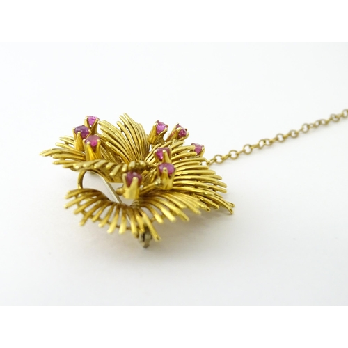 591 - An 18ct gold brooch / pendant of stylised floral form set with 9 rubies. Approx. 1 1/4