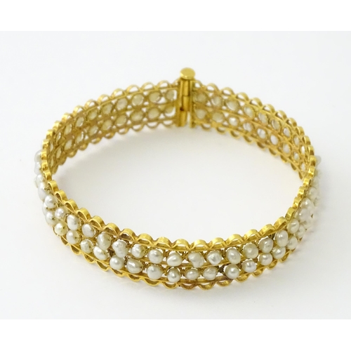 594 - A gold (tested) bracelet of bangle form set with two rows of banded pearls in a rope twist setting. ... 