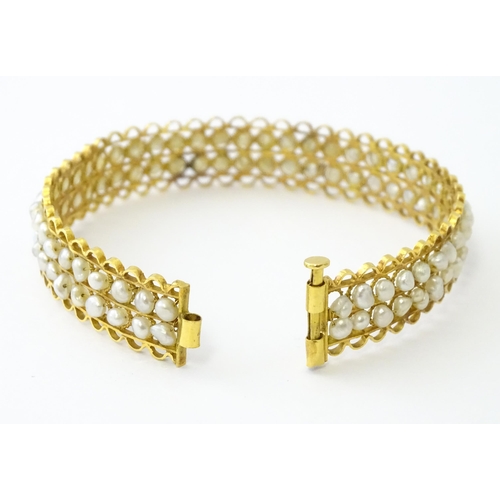 594 - A gold (tested) bracelet of bangle form set with two rows of banded pearls in a rope twist setting. ... 