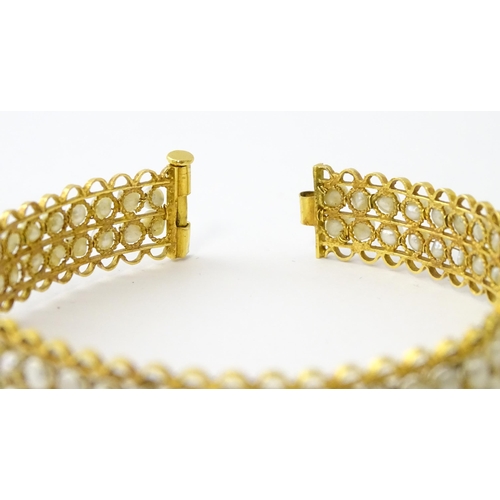 594 - A gold (tested) bracelet of bangle form set with two rows of banded pearls in a rope twist setting. ... 