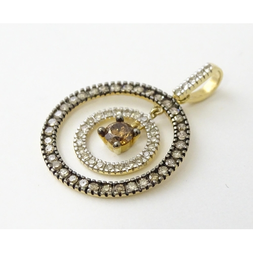 598 - A 14ct gold pendant of concentric circle form set with diamonds and having a central brown coloured ... 