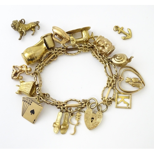 600 - A 9ct gold charm bracelet with padlock clasp, set with various charms, mostly 9ct gold to include te... 