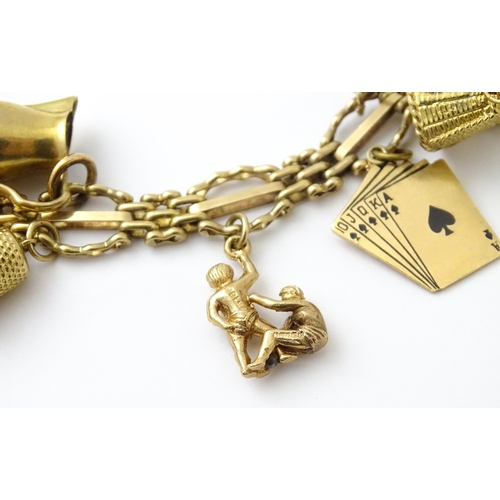 600 - A 9ct gold charm bracelet with padlock clasp, set with various charms, mostly 9ct gold to include te... 