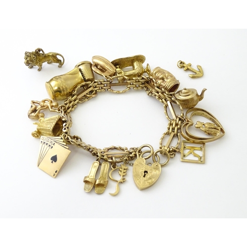 600 - A 9ct gold charm bracelet with padlock clasp, set with various charms, mostly 9ct gold to include te... 