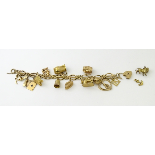 600 - A 9ct gold charm bracelet with padlock clasp, set with various charms, mostly 9ct gold to include te... 