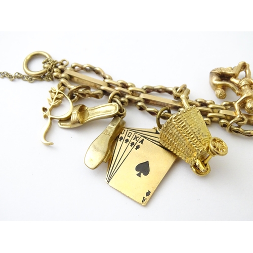 600 - A 9ct gold charm bracelet with padlock clasp, set with various charms, mostly 9ct gold to include te... 