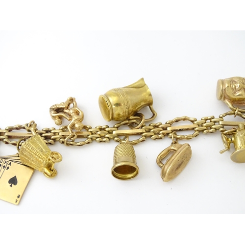 600 - A 9ct gold charm bracelet with padlock clasp, set with various charms, mostly 9ct gold to include te... 