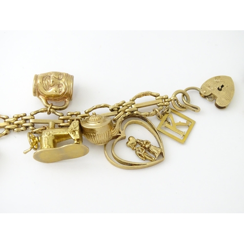 600 - A 9ct gold charm bracelet with padlock clasp, set with various charms, mostly 9ct gold to include te... 