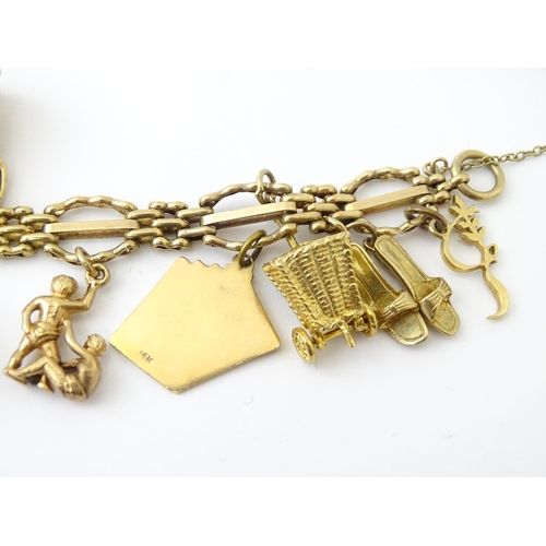 600 - A 9ct gold charm bracelet with padlock clasp, set with various charms, mostly 9ct gold to include te... 