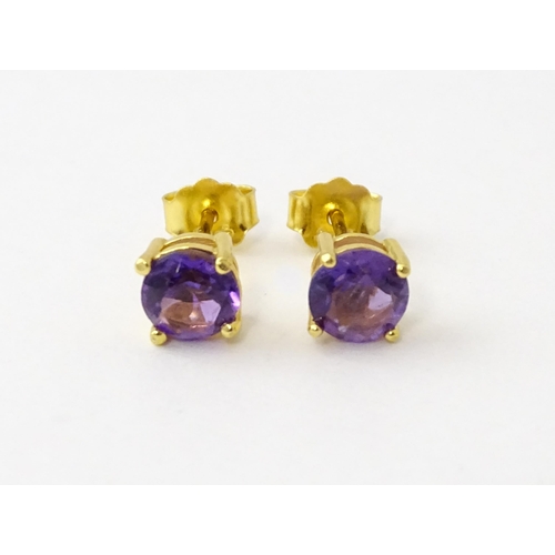 601 - A pair of .925 silver gilt stud earrings set with central amethyst. Approx. 1/4