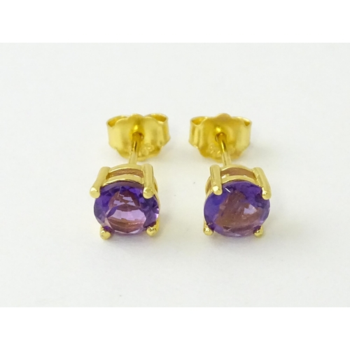 601 - A pair of .925 silver gilt stud earrings set with central amethyst. Approx. 1/4