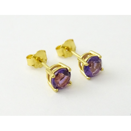 601 - A pair of .925 silver gilt stud earrings set with central amethyst. Approx. 1/4