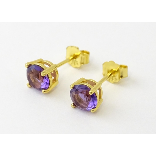 601 - A pair of .925 silver gilt stud earrings set with central amethyst. Approx. 1/4