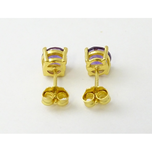 601 - A pair of .925 silver gilt stud earrings set with central amethyst. Approx. 1/4