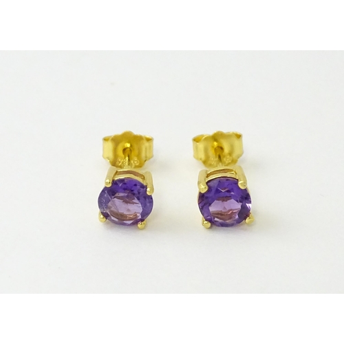 601 - A pair of .925 silver gilt stud earrings set with central amethyst. Approx. 1/4