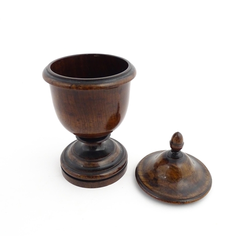 1166 - Treen : A 19thC turned wooden pedestal caddy of urn form with acorn finial. Approx. 9 1/4