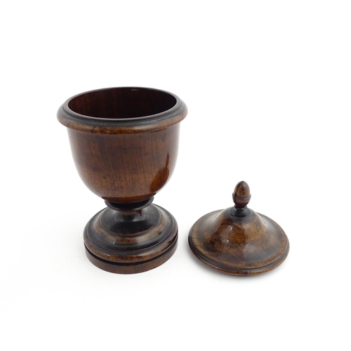 1166 - Treen : A 19thC turned wooden pedestal caddy of urn form with acorn finial. Approx. 9 1/4