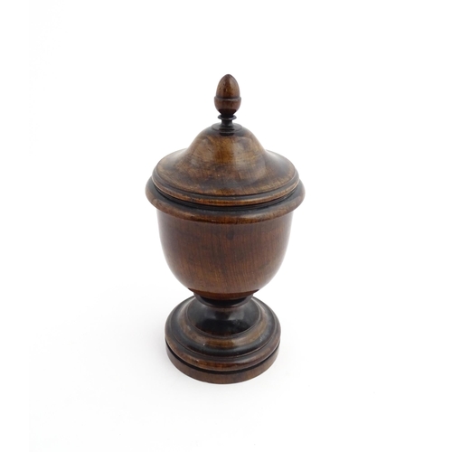 1166 - Treen : A 19thC turned wooden pedestal caddy of urn form with acorn finial. Approx. 9 1/4