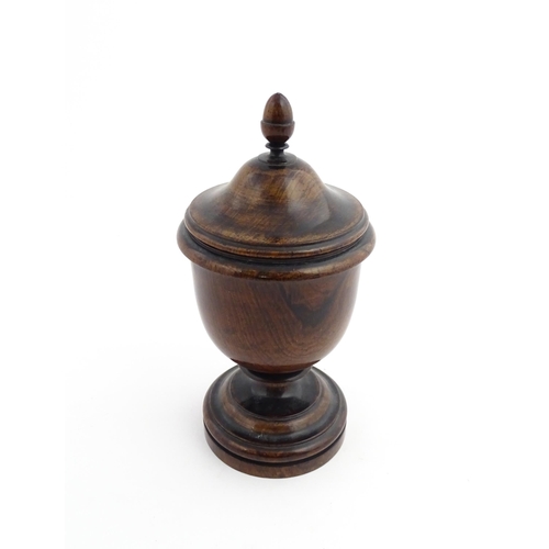 1166 - Treen : A 19thC turned wooden pedestal caddy of urn form with acorn finial. Approx. 9 1/4