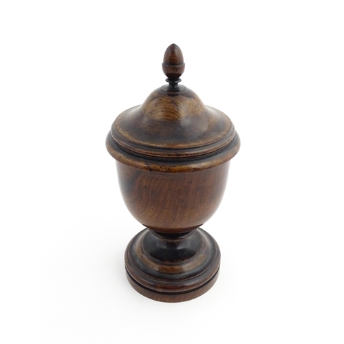 1166 - Treen : A 19thC turned wooden pedestal caddy of urn form with acorn finial. Approx. 9 1/4