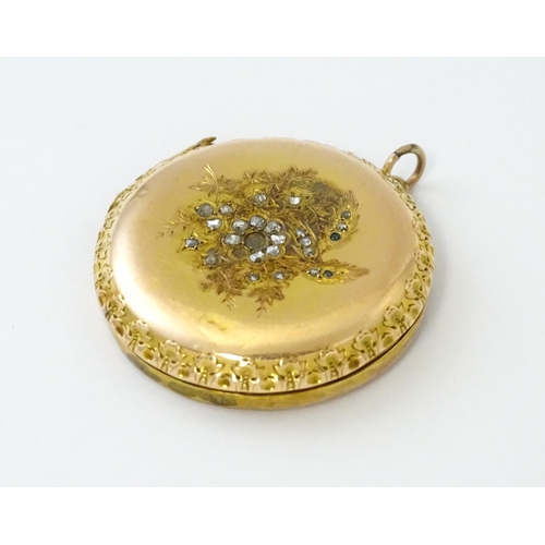 605 - A yellow gold pendant locket of circular form with foliate border and central floral detail set with... 