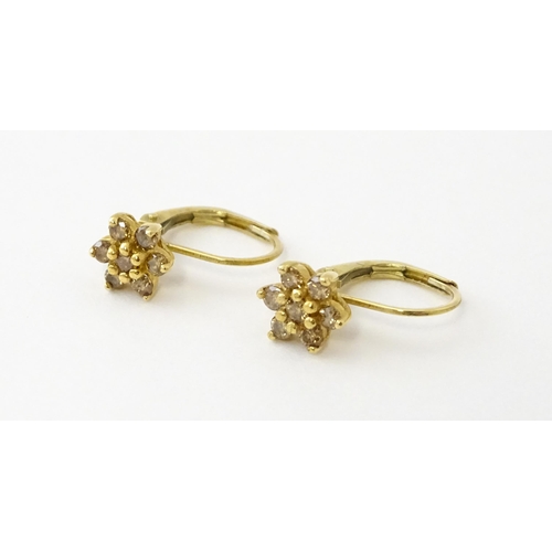 609 - A pair of 9ct gold earrings set with diamonds in a floral setting. Approx. 1/4