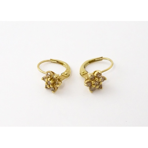 609 - A pair of 9ct gold earrings set with diamonds in a floral setting. Approx. 1/4