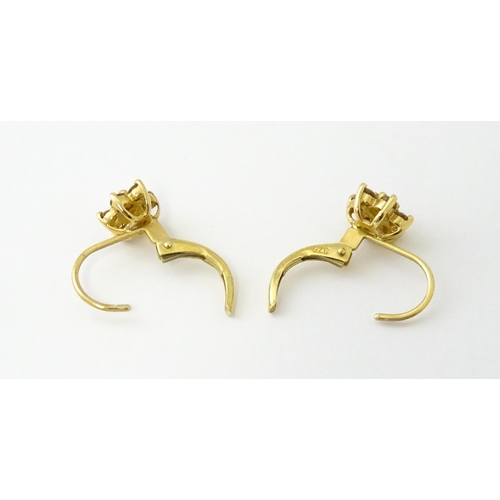 609 - A pair of 9ct gold earrings set with diamonds in a floral setting. Approx. 1/4