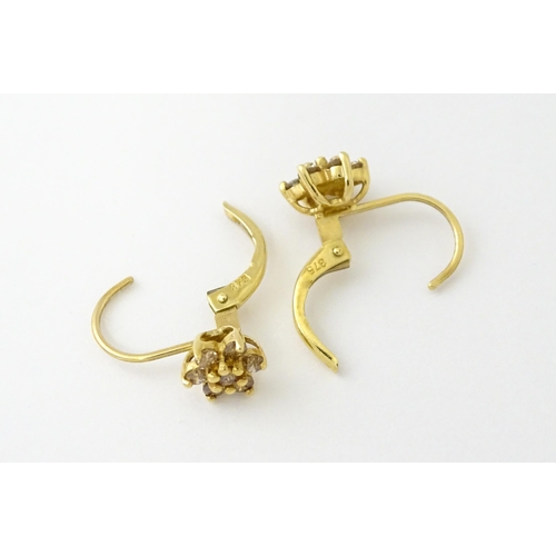 609 - A pair of 9ct gold earrings set with diamonds in a floral setting. Approx. 1/4