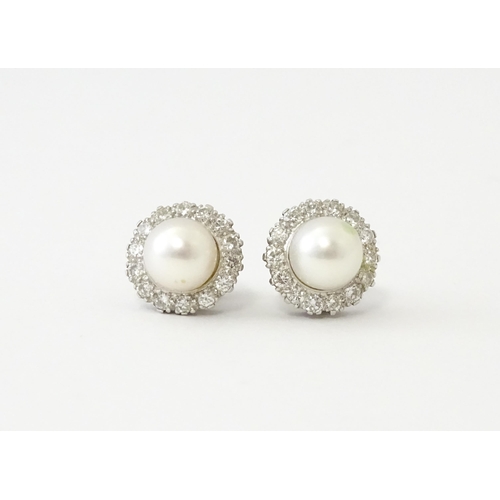 620 - A pair of 18ct white gold stud earrings with central cultured pearl bordered by 14 brilliant cut dia... 