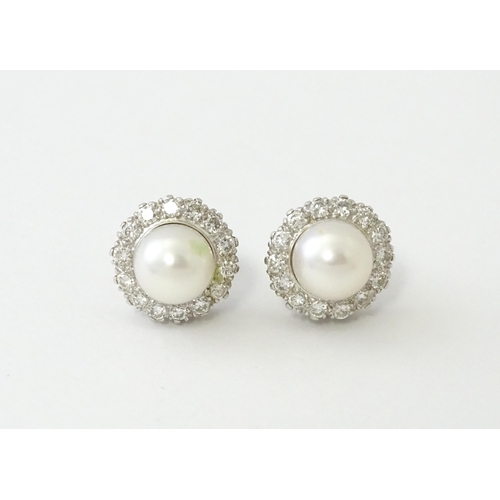 620 - A pair of 18ct white gold stud earrings with central cultured pearl bordered by 14 brilliant cut dia... 