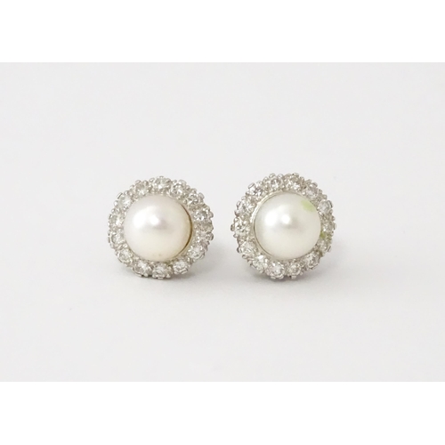 620 - A pair of 18ct white gold stud earrings with central cultured pearl bordered by 14 brilliant cut dia... 