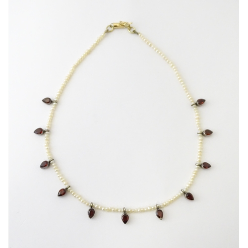 625 - A pearl choker necklace set with garnet with a yellow metal clasp. Approx. 14