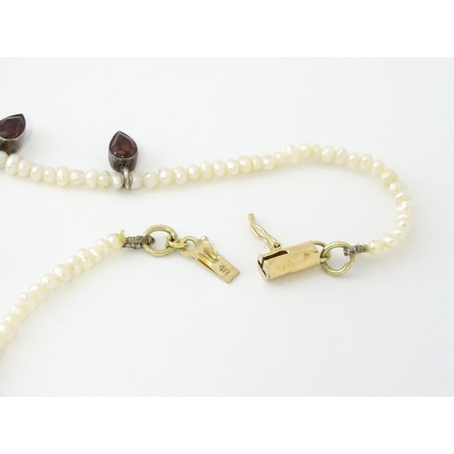 625 - A pearl choker necklace set with garnet with a yellow metal clasp. Approx. 14