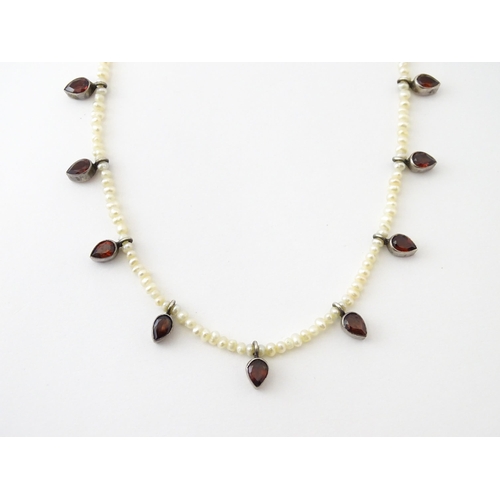 625 - A pearl choker necklace set with garnet with a yellow metal clasp. Approx. 14