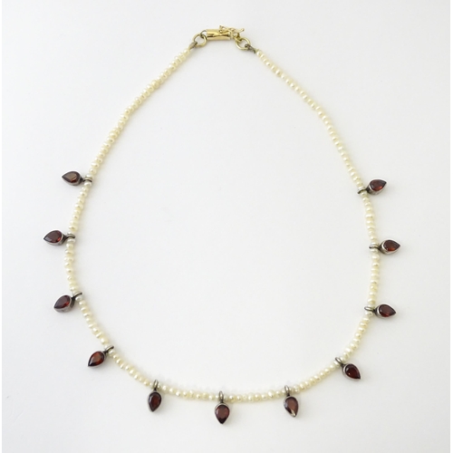 625 - A pearl choker necklace set with garnet with a yellow metal clasp. Approx. 14