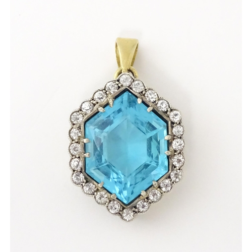 665 - A yellow metal pendant set with central blue stone bordered by white stones. Approx. 1 1/2